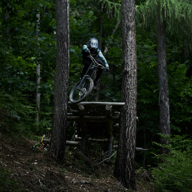mountain biker riding off of high platform in the forest
